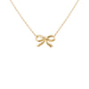 A delicate gold chain necklace featuring a small bow-shaped pendant, shown against a plain white background.