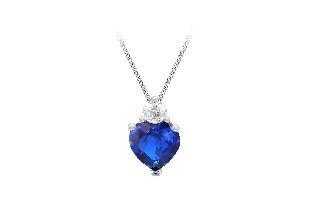 A heart-shaped blue gemstone pendant necklace in a silver-toned setting with a small clear stone above it, suspended from a silver chain on a white background.